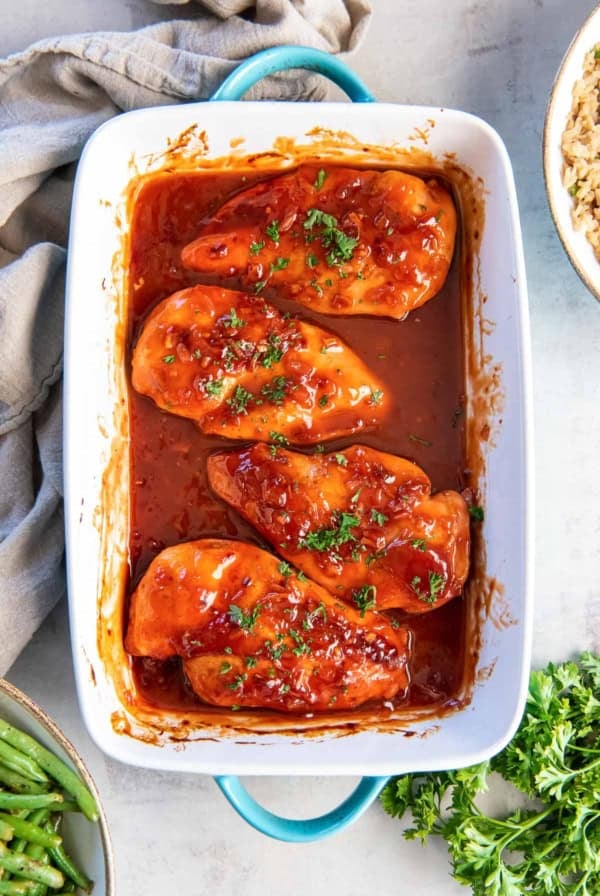 Chicken breasts topped with catalina dressing in a baking dish.