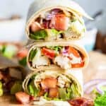 Chicken bacon ranch wraps sliced in half and stacked on a piece of parchment paper.