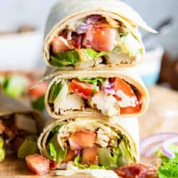 Chicken bacon ranch wraps sliced in half and stacked on a piece of parchment paper.