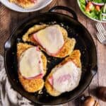 Malibu chicken with ham and swiss cheese in a cast iron skillet.