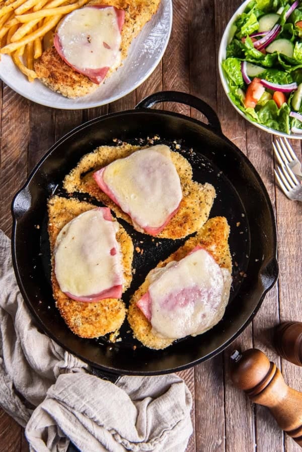 Malibu chicken with ham and swiss cheese in a cast iron skillet.