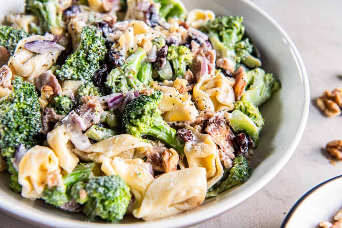 Tortellini broccoli salad with bacon and dried cranberries in a white serving bowl.