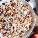 A large white bowl filled with apple coleslaw resting on a piece of burlap.