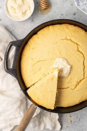 A spatula lifting a slice of cornbread from a cast iron skillet.