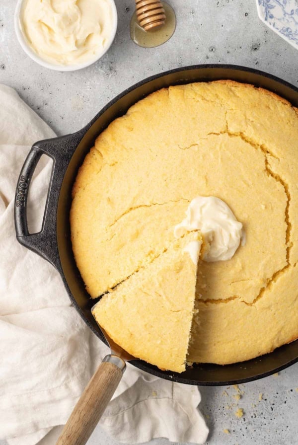 A spatula lifting a slice of cornbread from a cast iron skillet.
