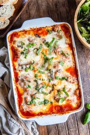 Baked ravioli topped with melted mozzarella cheese in a baking dish.