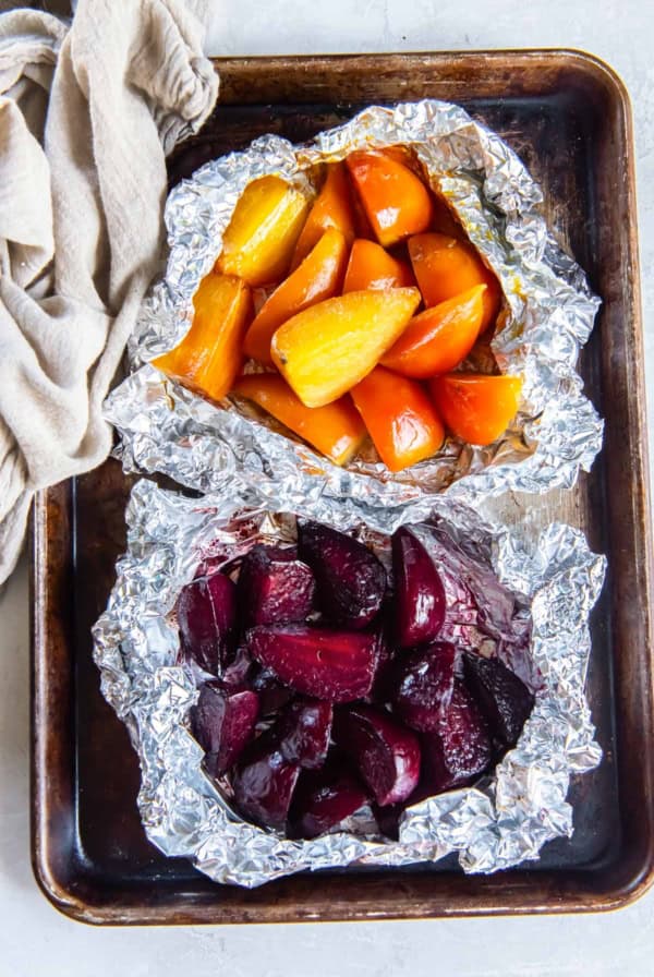 Roasted beets in foil packets on a baking sheet.