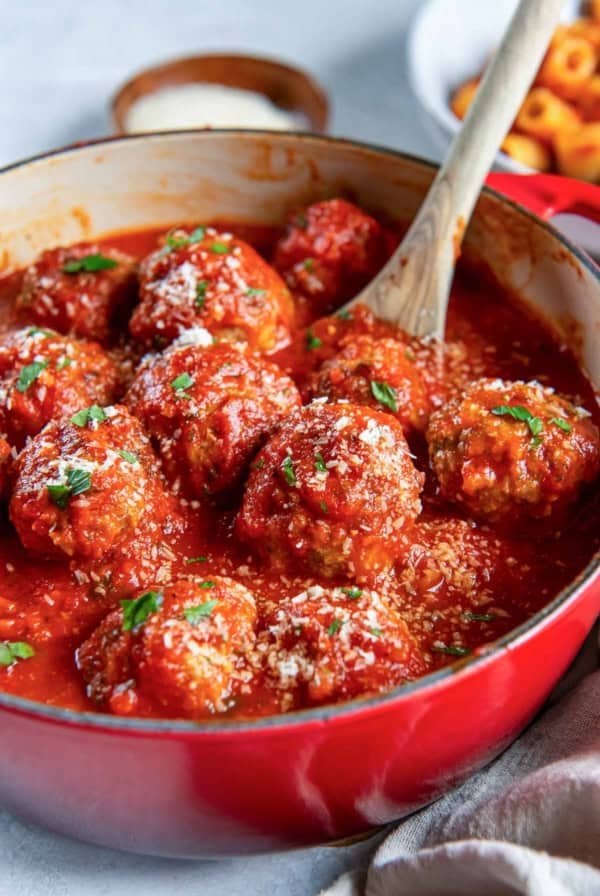 A spoon resting in a pot of Italian meatballs in marinara sauce.