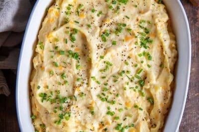 Make-ahead mashed potatoes topped with chives in a white baking dish.