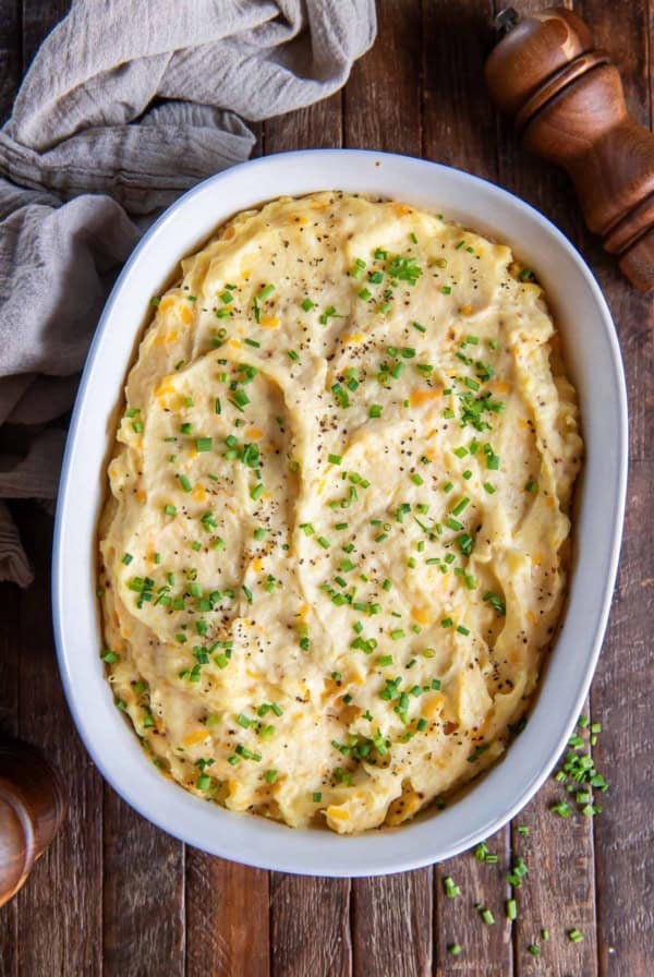 Make-ahead mashed potatoes topped with chives in a white baking dish.