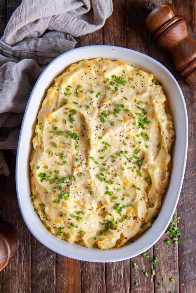 Make-ahead mashed potatoes topped with chives in a white baking dish.