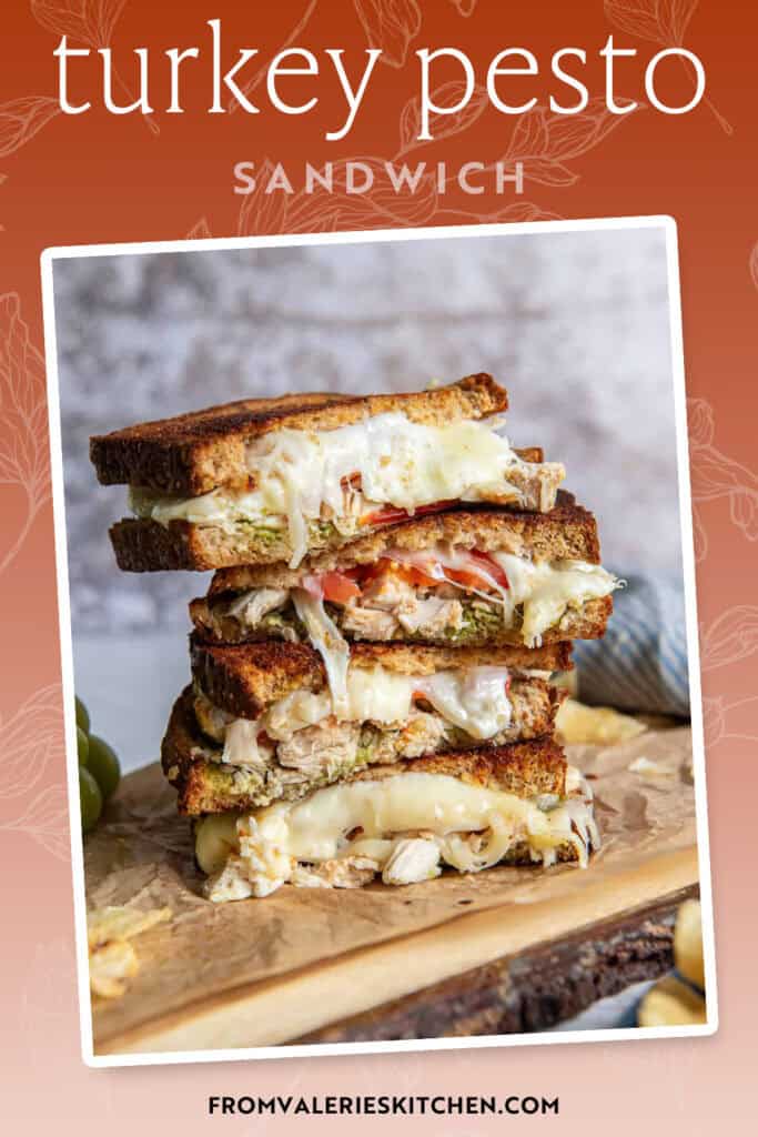 A sliced turkey pesto sandwich stacked on a wood board with text overlay.