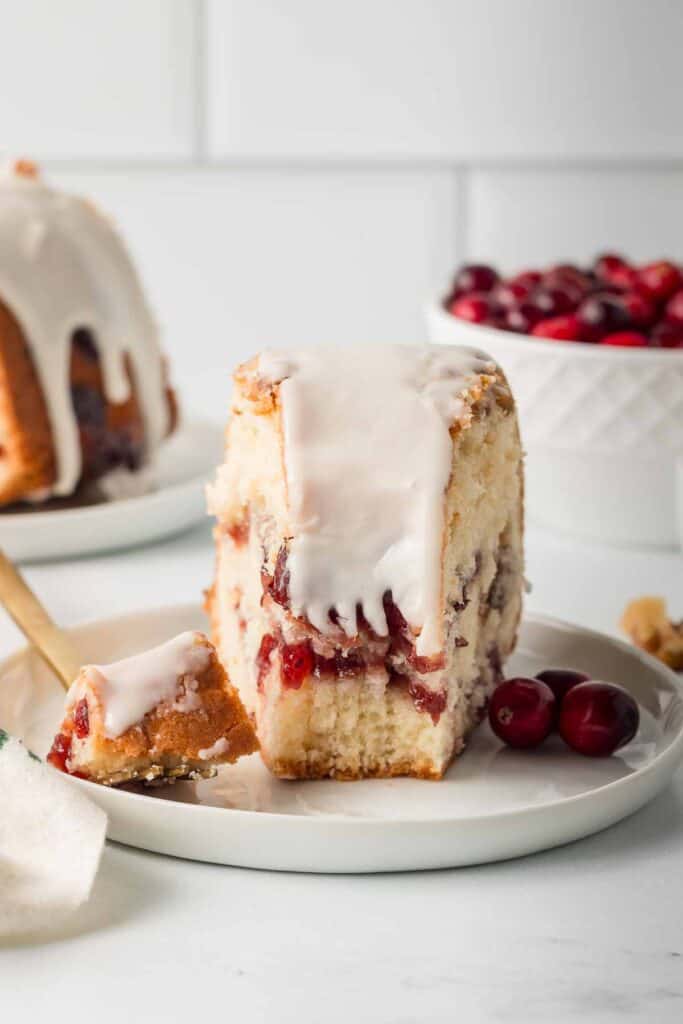 A fork resting on a plate with a slice of cranberry bundt cake.