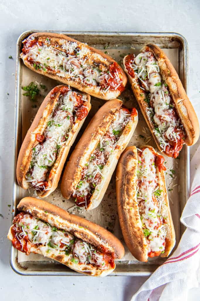 Turkey meatball subs with marinara and melted cheese on a baking sheet.