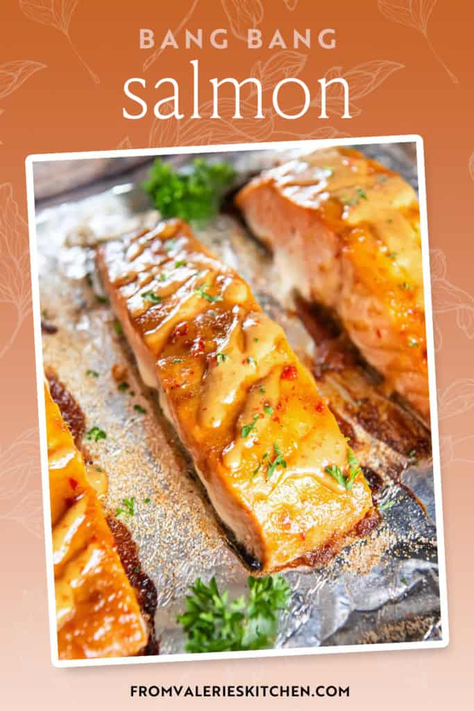 Salmon fillets with bang bang sauce on a foil lined baking sheet with text overlay.