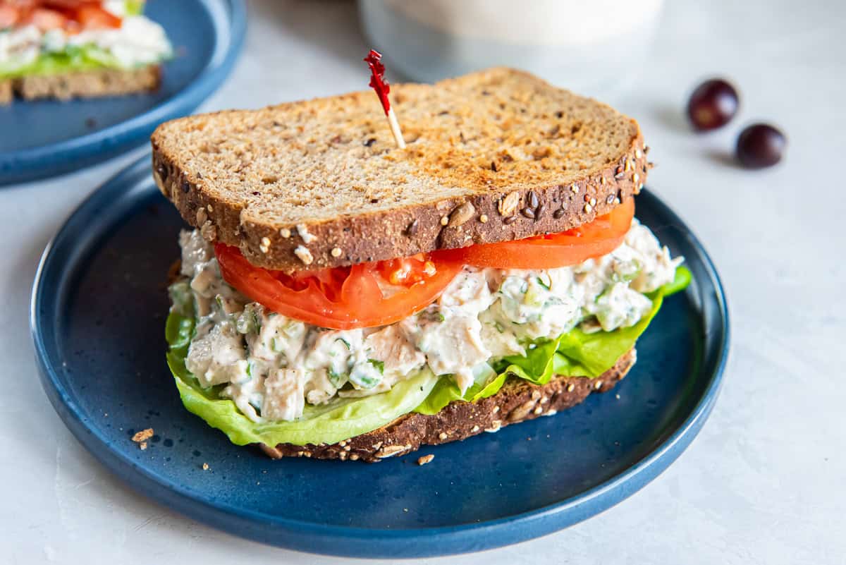 A chicken salad sandwich on toasted wheat bread on a blue plate.