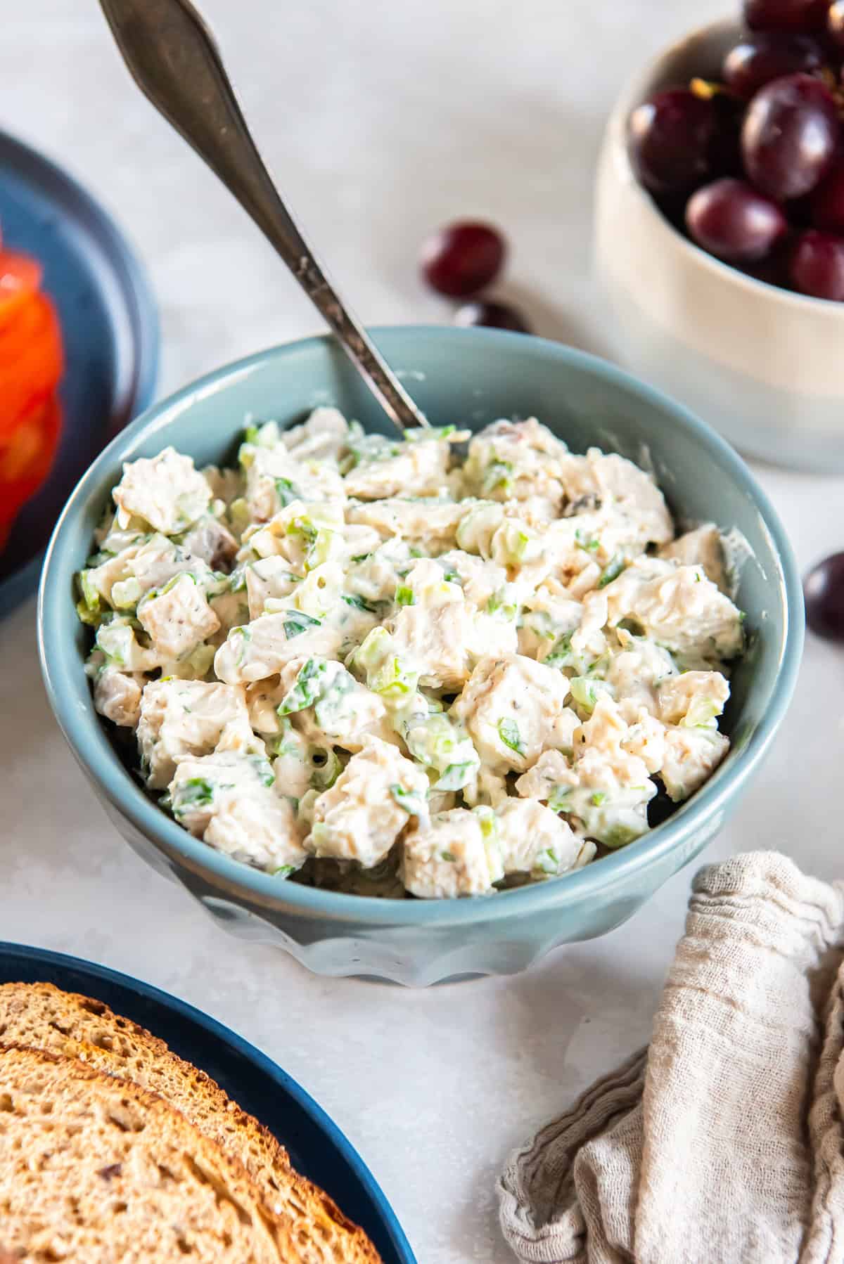 A spoon resting in a bowl of classic chicken salad for sandwiches.