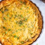 A ham and cheese crustless quiche in a white quiche pan.