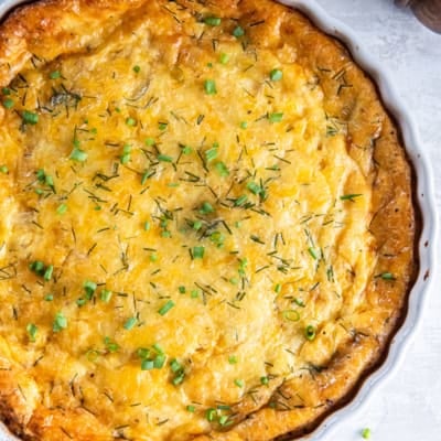 A ham and cheese crustless quiche in a white quiche pan.