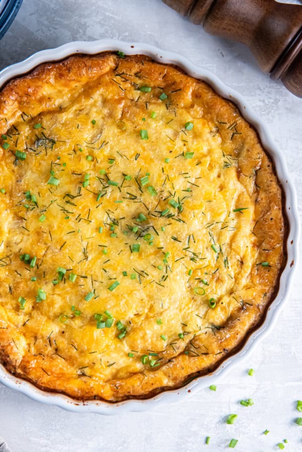 A ham and cheese crustless quiche in a white quiche pan.