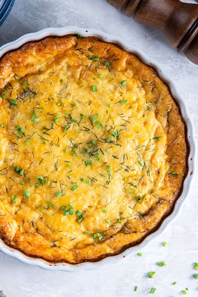 A ham and cheese crustless quiche in a white quiche pan.