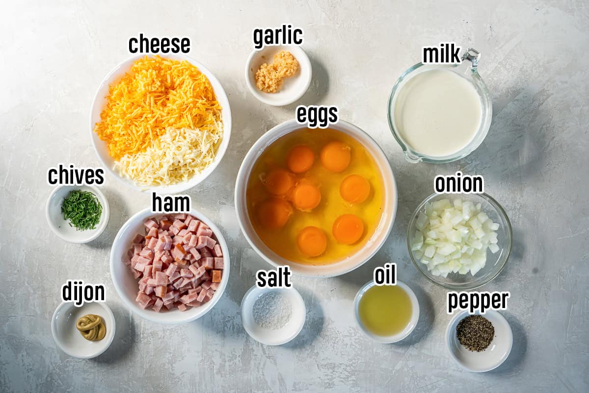 Eggs, milk, cheese, ham and other ingredients in bowls with text overlay.