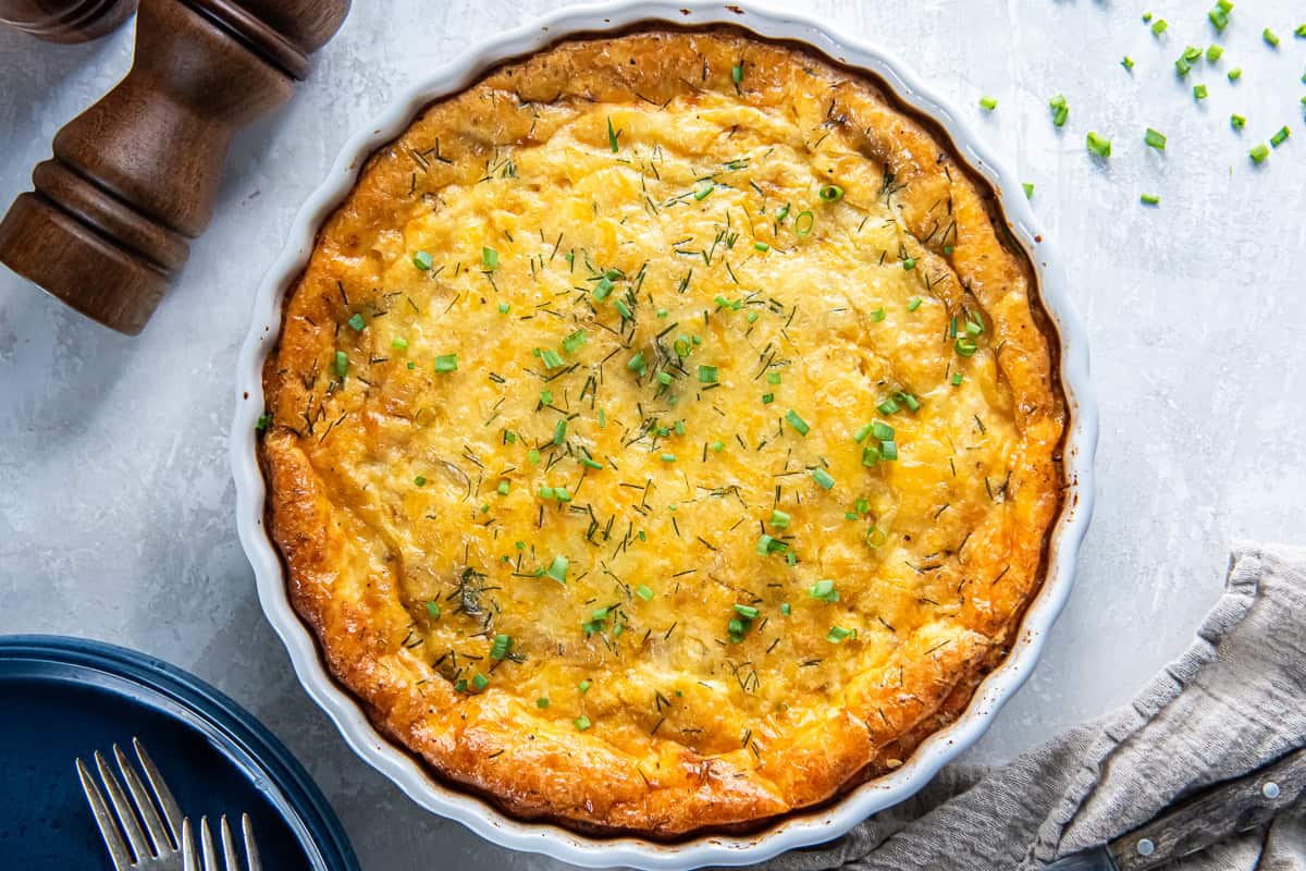 Ham and cheese crustless quiche in a white dish next to a pepper shaker.