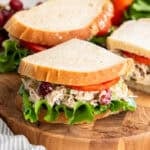A copycat Panera chicken salad sandwich sliced and resting on a cutting board.