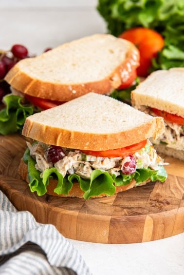 A copycat Panera chicken salad sandwich sliced and resting on a cutting board.