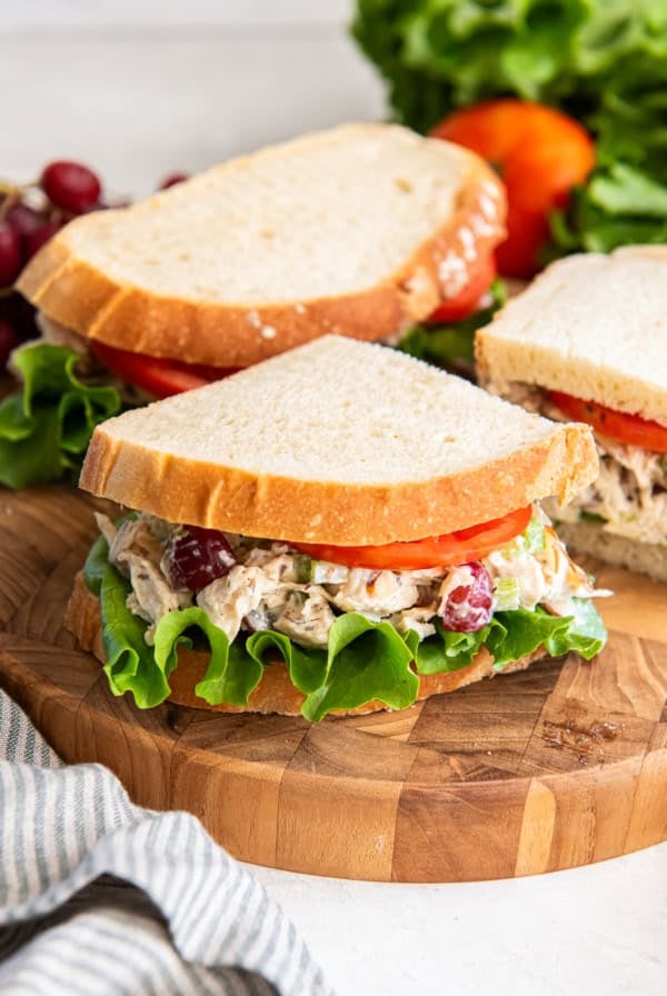 A copycat Panera chicken salad sandwich sliced and resting on a cutting board.