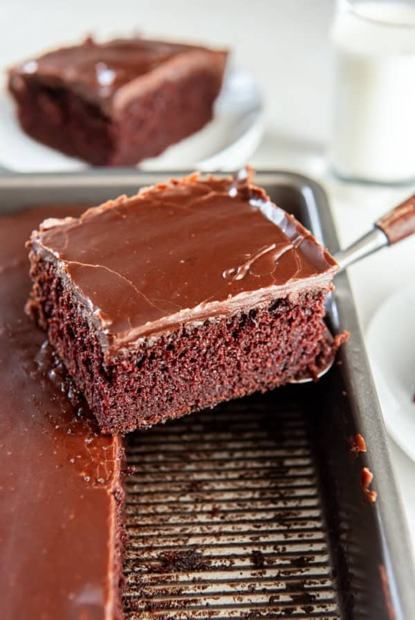 A spatula lifting a slice of chocolate cake from a cake pan.