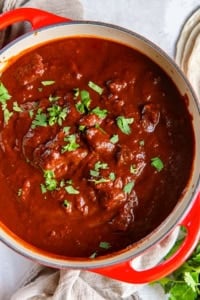 A large pot filled with chile colorado and garnished with cilantro.