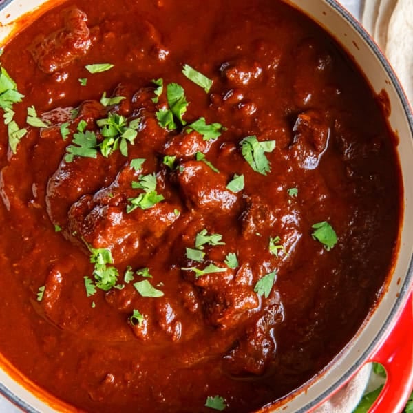 A large pot filled with chile colorado and garnished with cilantro.