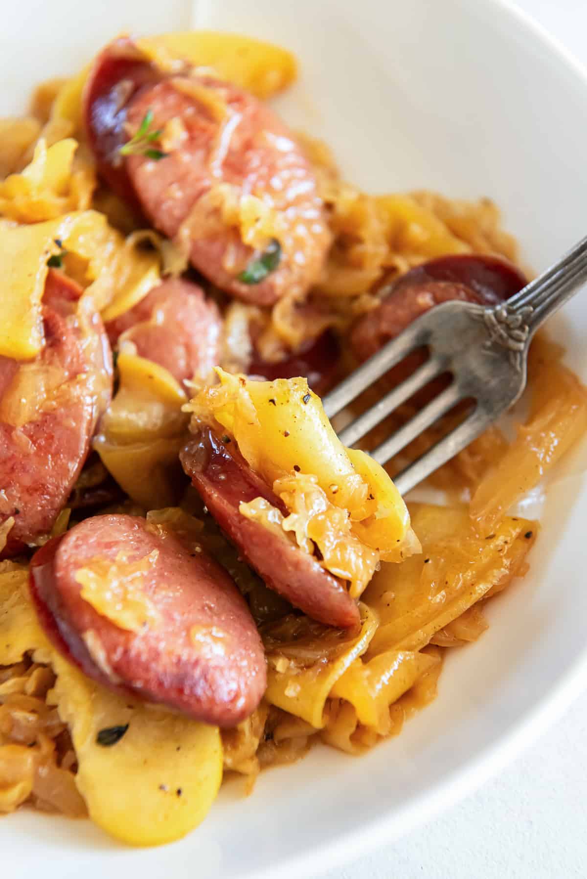 A fork in a bowl of kielbasa and sausage.