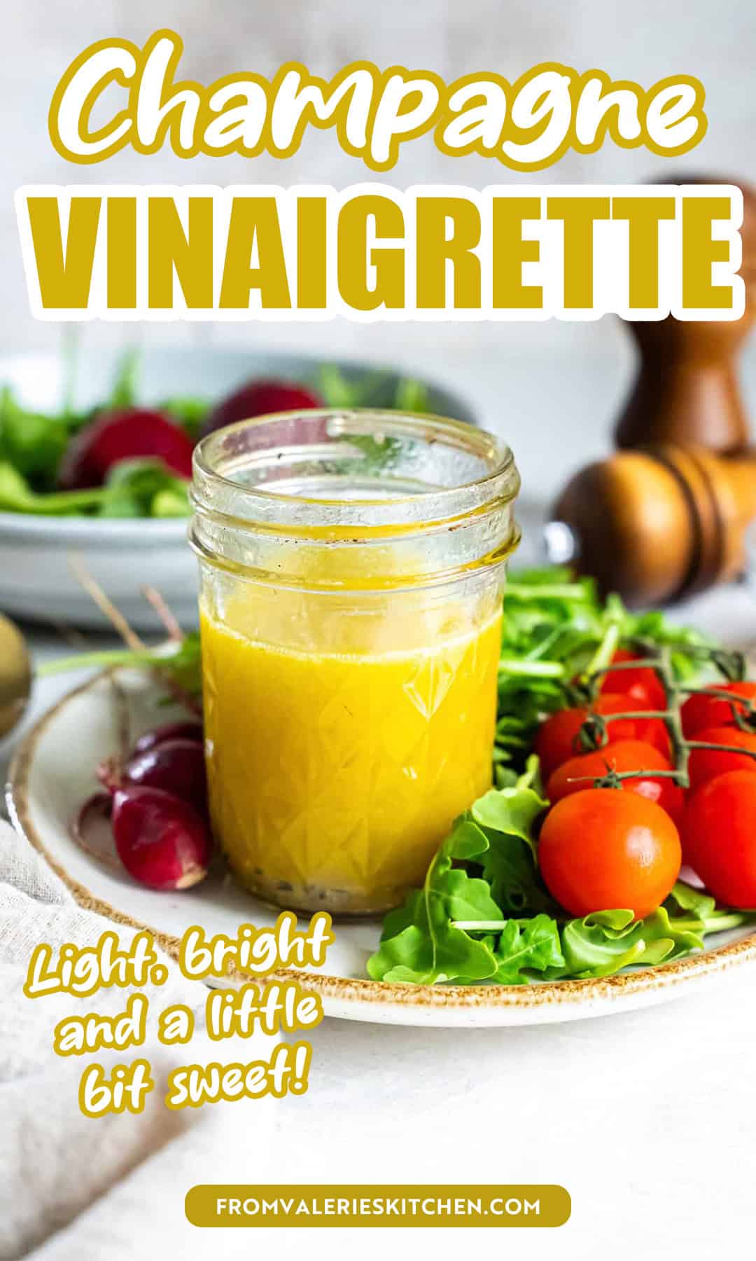 Champagne vinaigrette in a mason jar on a plate with cherry tomatoes with text overlay.