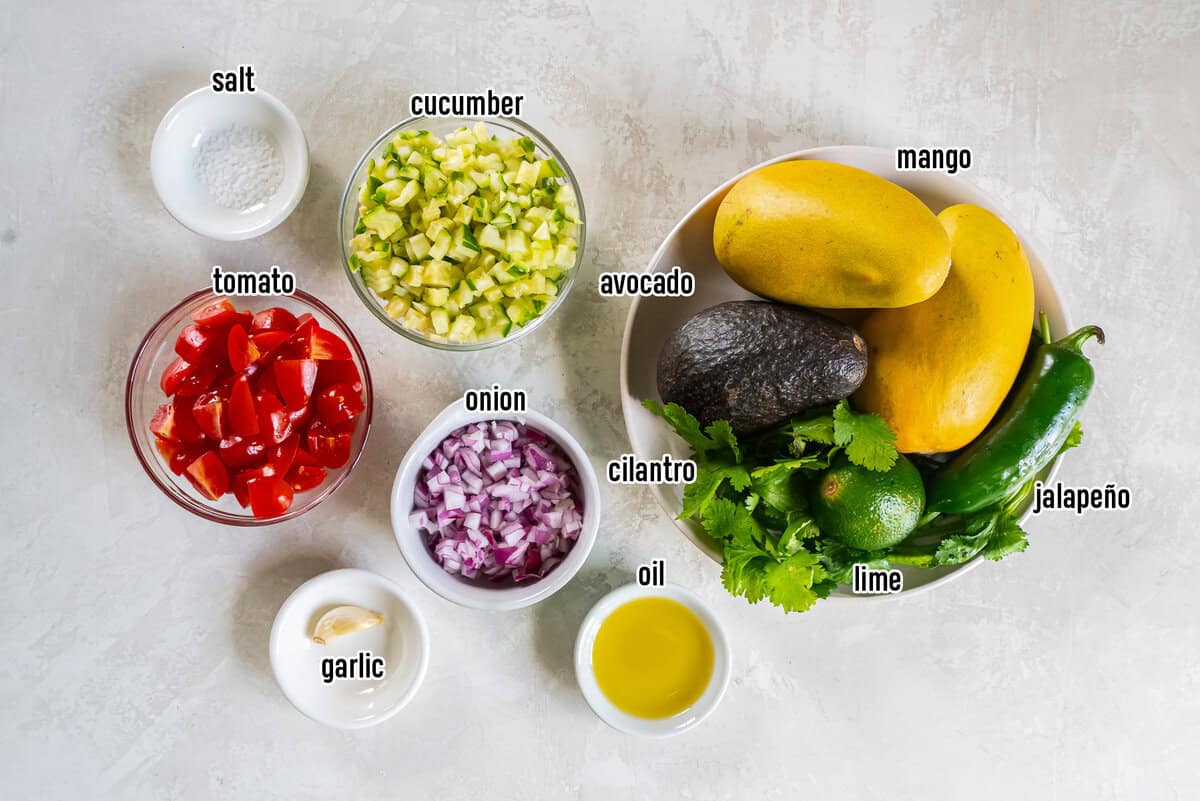 Mangoes, jalapeno, cucumber, avocado, and other ingredients in bowls with text overlay.