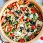 A wood bowl filled with pizza pasta salad.
