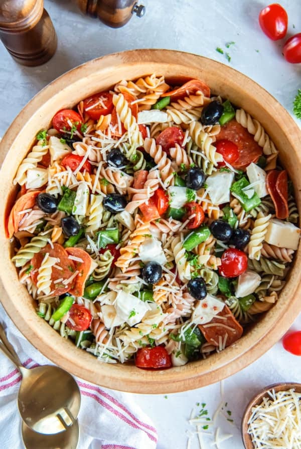 A wood bowl filled with pizza pasta salad.