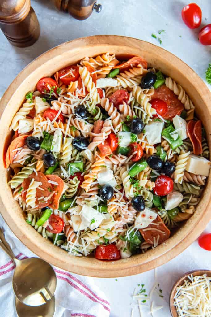 A wood bowl filled with pizza pasta salad.