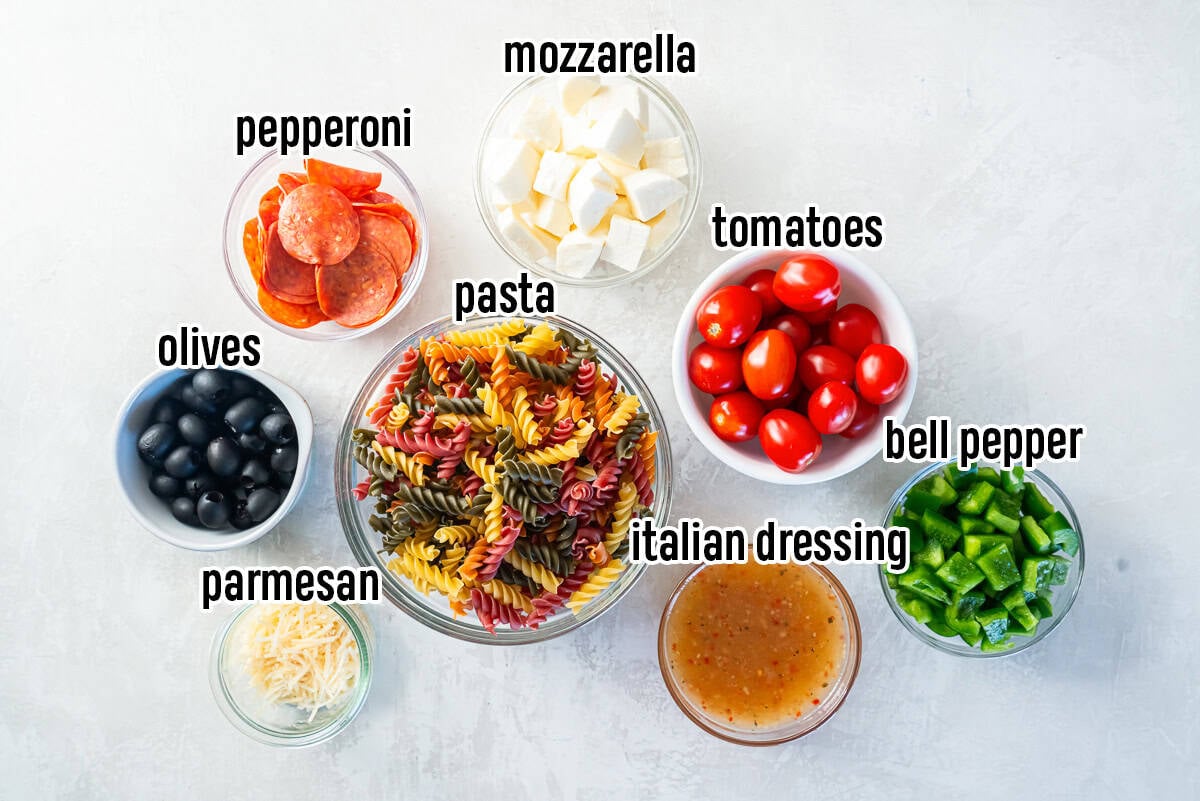 Pizza Pasta Salad 4 Colored spiral pasta, tomatoes, olives, and other ingredients in bowls with text overlay.