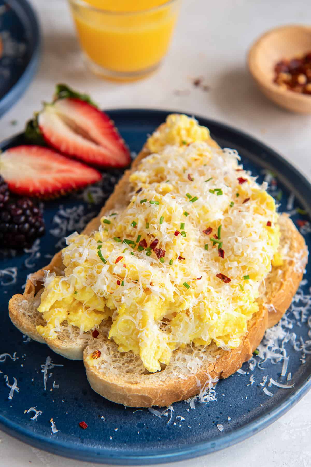 Toast topped with ricotta eggs on a blue plate with berries.