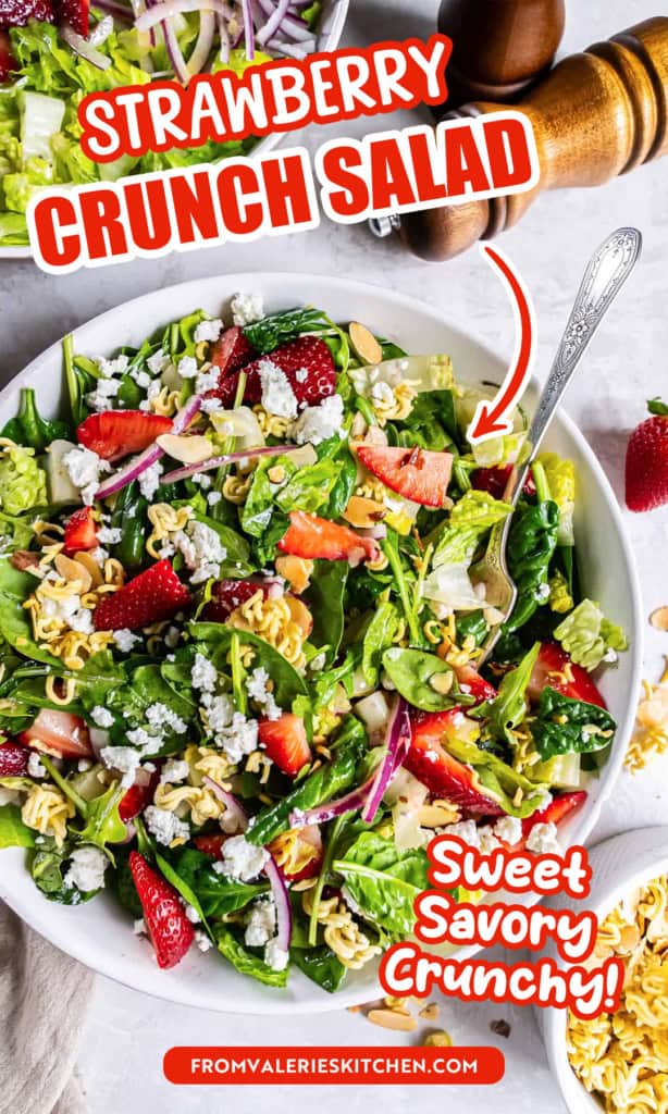 A salad with greens, strawberries, ramen noodles, and goat cheese in a large round white bowl with text overlay.