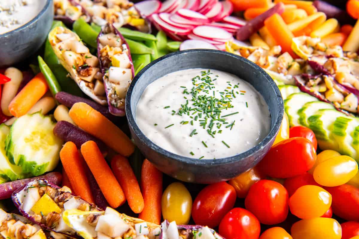 A crudity platter with assorted vegetables, stuffed endive, and creamy dips.