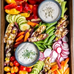 A crudite platter with assorted vegetables and two dips in small bowls.