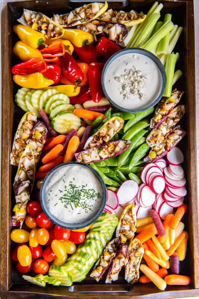 A crudite platter with assorted vegetables and two dips in small bowls.