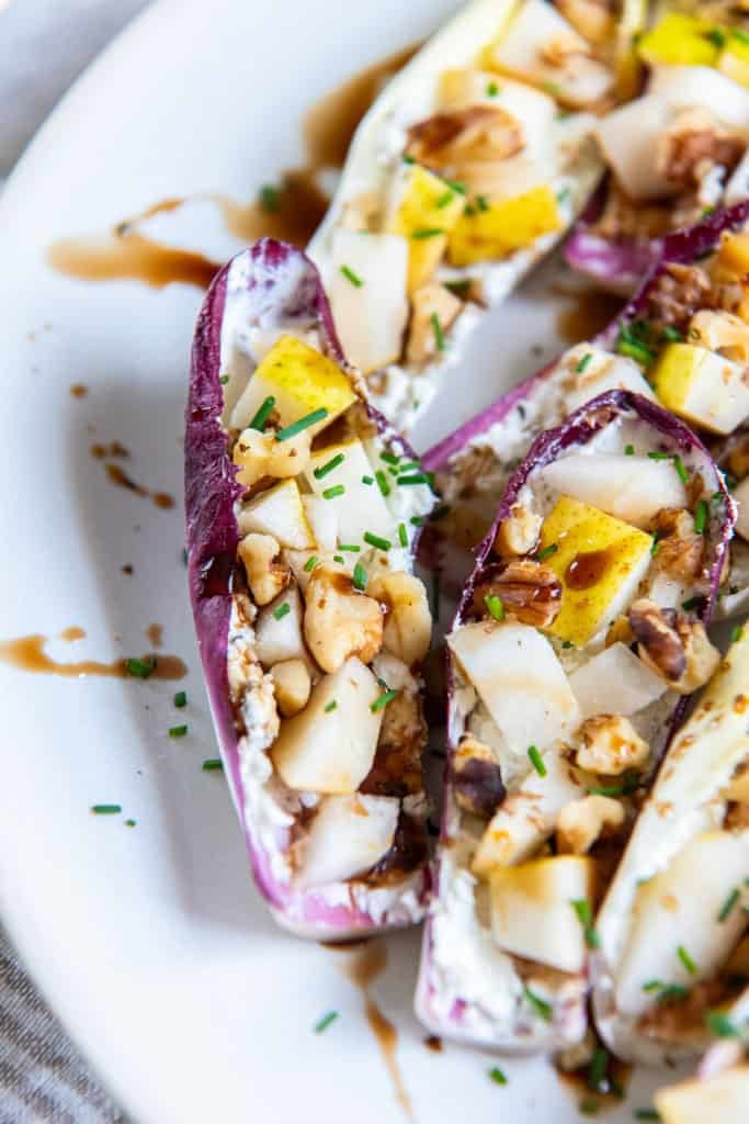 Stuffed endive with balsamic glaze on a white plate.