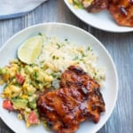 Grilled chipotle maple chicken in white bowls with rice and mango salsa.