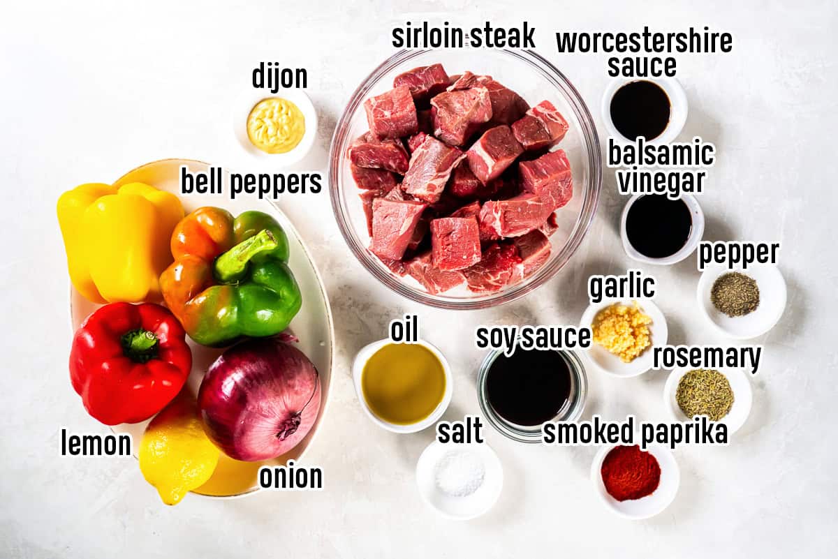 Cubed steak, bell peppers, a red onion, a lemon, soy sauce, and other ingredients in bowls with text overlay.