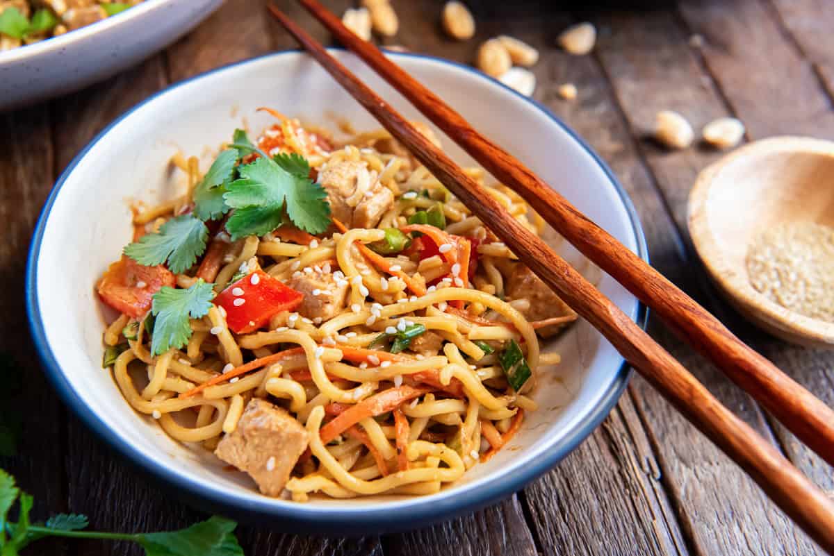Peanut Noodles with Chicken 5 Chopsticks resting on a small bowl filled with peanut noodles with chicken.