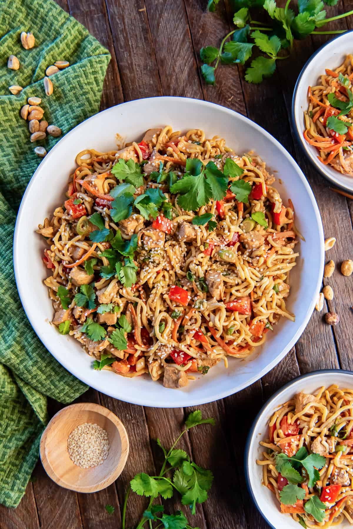 Peanut Noodles with Chicken 2 Peanut noodles with chicken in a large white bowl next to a small bowl of sesame seeds.